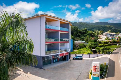 a white building with a palm tree in front of it at Thalassa Seychelles in Beau Vallon