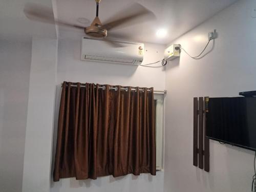 a room with a ceiling fan and a curtain at Aahvaanam in Kurnool