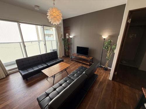 a living room with black leather couches and a table at Cozy house! 4 Mins from Hisaya-Odori station in Nagoya