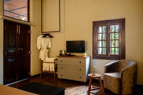 a living room with a tv and a chair and a dresser at Tathya Hills - Luxe Garden Retreat In The Hills in Nuwara Eliya