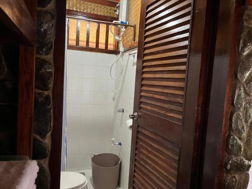 a bathroom with a toilet and a wooden door at MALAIKA RESORT in San Vicente