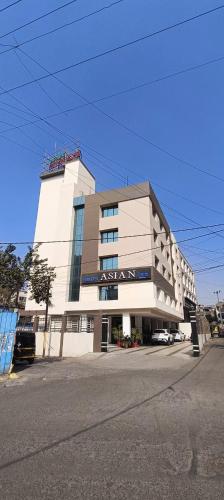 a large white building on the side of a street at Hotel Asian Inn, Nagpur in Nagpur