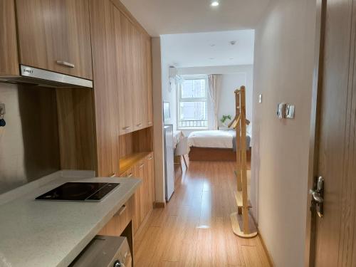 a kitchen with wooden cabinets and a room with a bed at Sunnycove Homestay in Qingdao