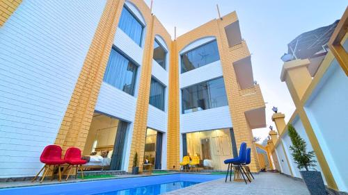 a building with red and blue chairs next to a swimming pool at Asapin Vanymahal in Rāmnagar