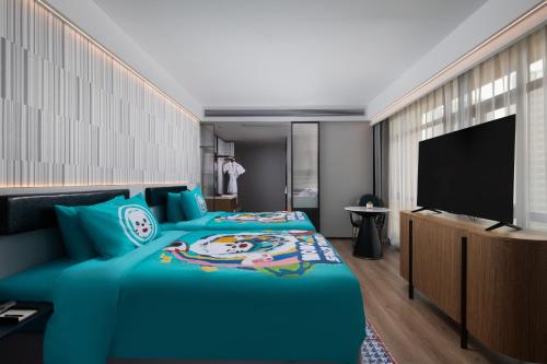 a bedroom with a blue bed and a flat screen tv at Wanda Moments Nanchang Xihu in Nanchang