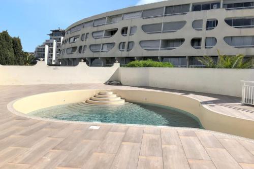 une piscine circulaire au milieu d'un bâtiment dans l'établissement Appartement charmant au Grau-du-Roi avec piscine partagée, au Grau-du-Roi
