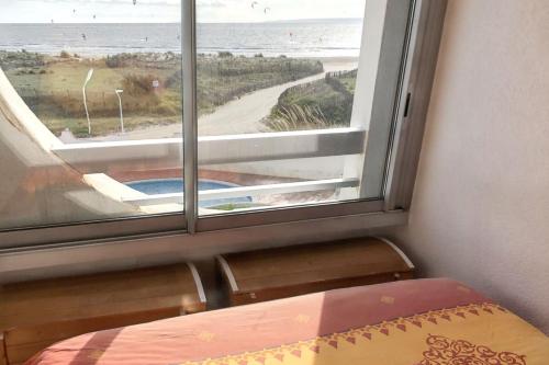 a bedroom with a window with a view of the beach at Appartement charmant au Grau-du-Roi avec piscine partagée in Le Grau-du-Roi
