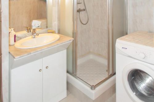 a bathroom with a sink and a shower and a washing machine at Appartement charmant au Grau-du-Roi avec piscine partagée in Le Grau-du-Roi