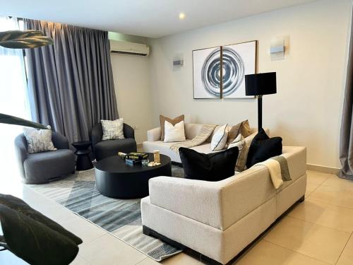 a living room with a couch and chairs and a table at Wonder Nest Dar es salaam in Dar es Salaam