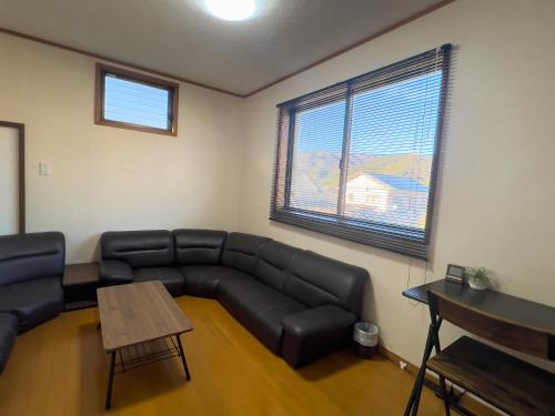 a living room with a leather couch and a table at ハートリサイデェンス 河津 in Kawazu