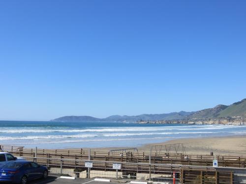 a beach with a car parked next to the ocean at Dolphin Cove Motel in Pismo Beach