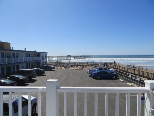 a parking lot next to the beach with a pier at Dolphin Cove Motel in Pismo Beach