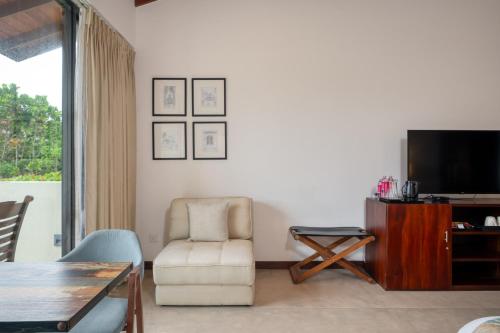 a living room with a tv and a chair and a table at Mirissa Beach Villa in Mirissa