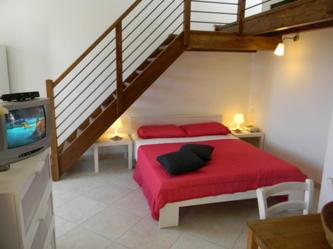 sypialnia z czerwonym łóżkiem i schodami w obiekcie Casa di Livia w mieście SantʼAnna Arresi