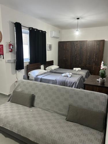 a hotel room with two beds and a couch at St gaetans studio apartment 6A in Tas-Samra