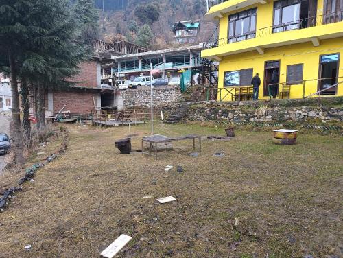 a person standing in front of a yellow building at Undiscovered Mountains Hotel and Restaurant in Jibhi