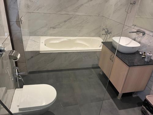 a bathroom with a tub and a toilet and a sink at Hotel Exotic - 5 min walk from Golden Temple in Amritsar