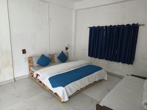 a bedroom with a large bed with blue pillows at Undiscovered Mountains Hotel and Restaurant in Jibhi