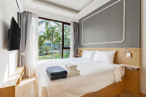 une chambre avec un lit blanc avec une fenêtre dans l'établissement Large condo Surin-Bangtao Beach, à Ban Lum Fuang