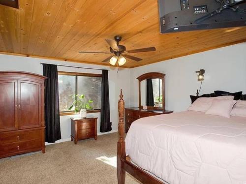 Un dormitorio con una cama y un ventilador de techo. en Sandalwood, en Pine Mountain Club