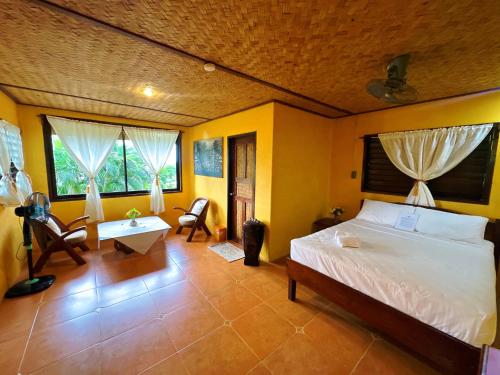 a bedroom with a bed and a desk and two windows at Casa Rosa Inn and Restaurant in Taytay