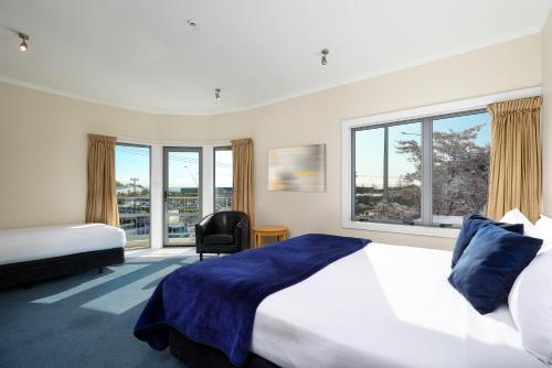 a bedroom with two beds and a chair and windows at Saxton Lodge in Nelson