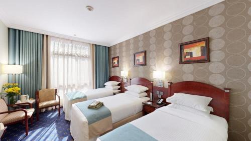 a hotel room with three beds and a sitting area at Al Muna Kareem Hotel- EX LEADER in Al Madinah