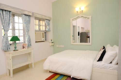 a white bedroom with a bed and a mirror at Casa Sea-Esta, Beach view studio apt - Dona Paula in Panaji