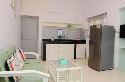 a kitchen with a couch and a refrigerator and a table at Casa Sea-Esta, Beach view studio apt - Dona Paula in Panaji