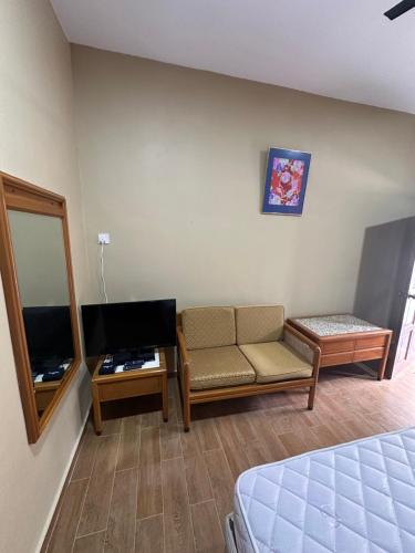 a room with a couch and a tv and a mirror at Santai Salai Homestay and Cafe in Kepala Batas