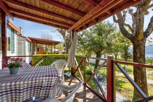 a wooden deck with a table and chairs and a tree at Camping Royal in Pettenasco
