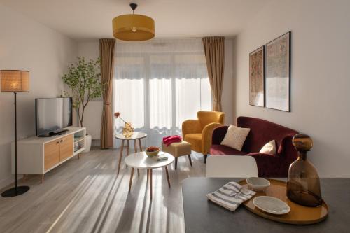 a living room with a couch and a tv at Domitys La Clef des Arts in Châlons-en-Champagne