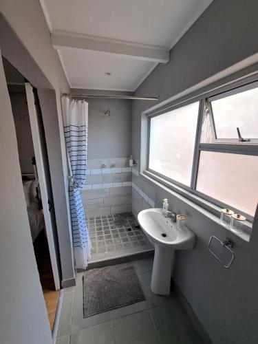 Un baño con lavabo blanco y ducha. en Mons Pes in Lakeside, en Ciudad del Cabo