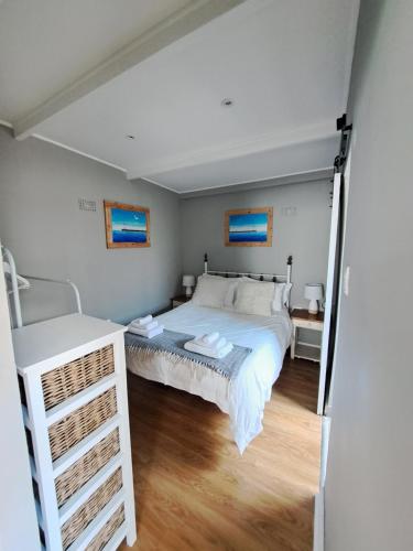 Un dormitorio con una cama blanca y suelo de madera. en Mons Pes in Lakeside, en Ciudad del Cabo