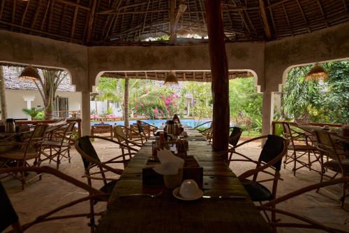 a long wooden table in a restaurant with chairs at African Bungalows in Nungwi