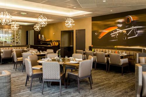 a restaurant with tables and chairs and a painting on the wall at Hotel Le Paddock in Magny-Cours