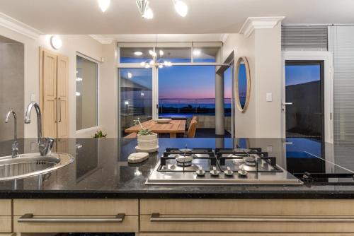 cocina con fogones y vistas al océano en "Villa Montemar' Luxury Villa for 6 on the Beach with Pool, en Gordonʼs Bay