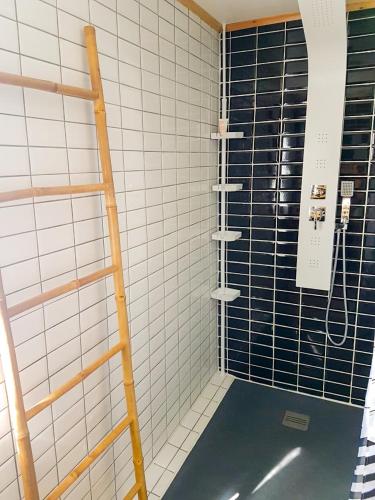 a shower with black and white tiled walls at Au Châlet in Le Tampon