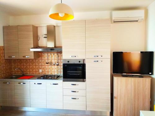 una cucina con armadi in legno, forno a microonde e TV di Meridiana, 2 Bedrooms a Caorle