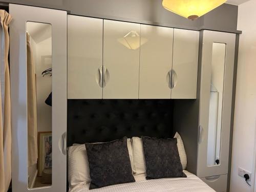 a bedroom with a black headboard and white cabinets at Harbour Penthouse Whitby in Whitby