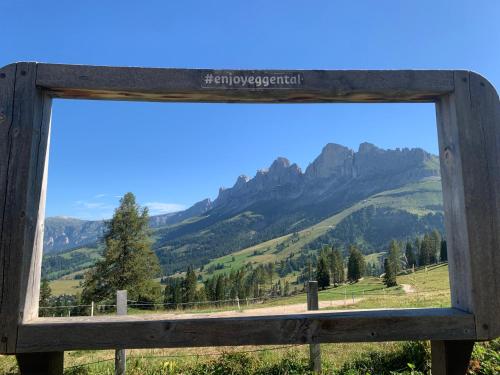 a view of the mountains through a wooden window at Hotel Dosses in Tires
