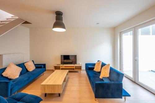 a living room with blue couches and a tv at Temse city center in Temse