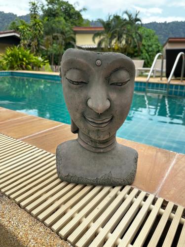a statue of a head sitting on a bench next to a pool at Escape-Cabins in Ko Lanta