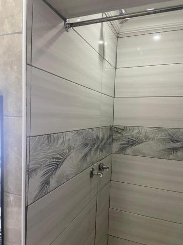 a shower with a glass door with a faucet at Bennyz Guest House in Pretoria