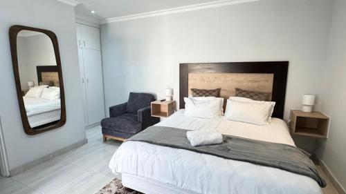 a bedroom with a large bed and a mirror at The Shifting Whispering Sands Guesthouse in Walvis Bay
