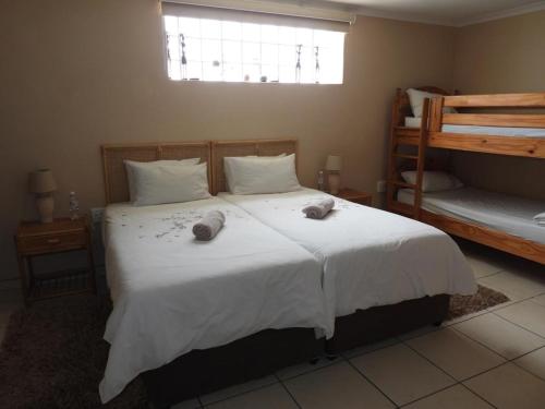 a bedroom with a large white bed with towels on it at The Shifting Whispering Sands Guesthouse in Walvis Bay