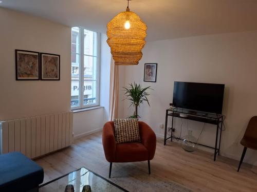 a living room with a chair and a flat screen tv at Joli appartement au coeur de Mâcon in Mâcon