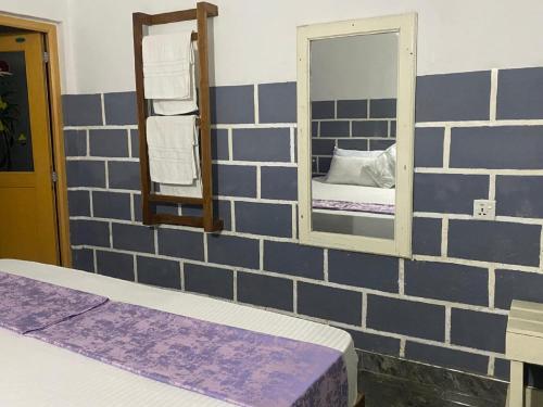 a bedroom with a brick wall with a mirror and a bed at Edy's Nest in Dambulla