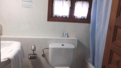 baño con aseo y lavabo y ventana en Hostal Puente Deva, en Espinama