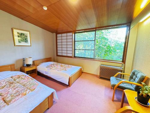 伊東市にある貸温泉リゾートBLOOMのベッドルーム1室(ベッド2台、窓、椅子付)